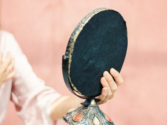 A woman's hand holding a oval-shaped vanity mirror