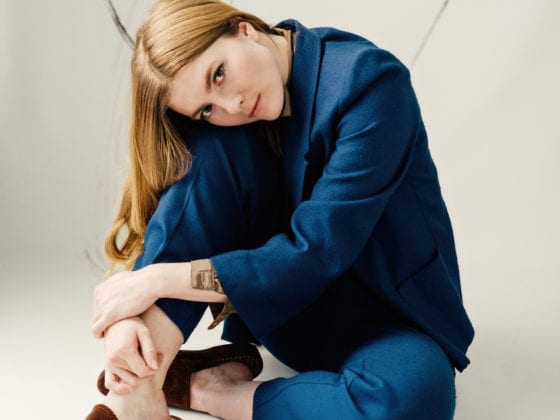 A woman in a navy blue suit crouched on the floor