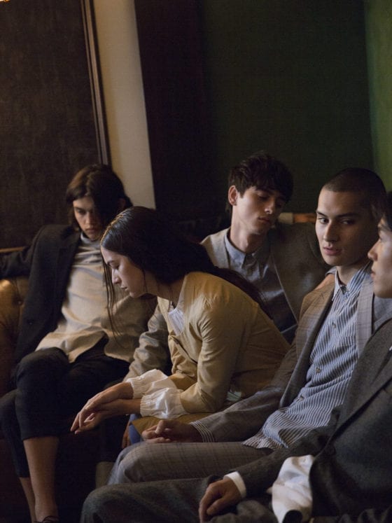 A group of five young adults seated on a couch in professional attire
