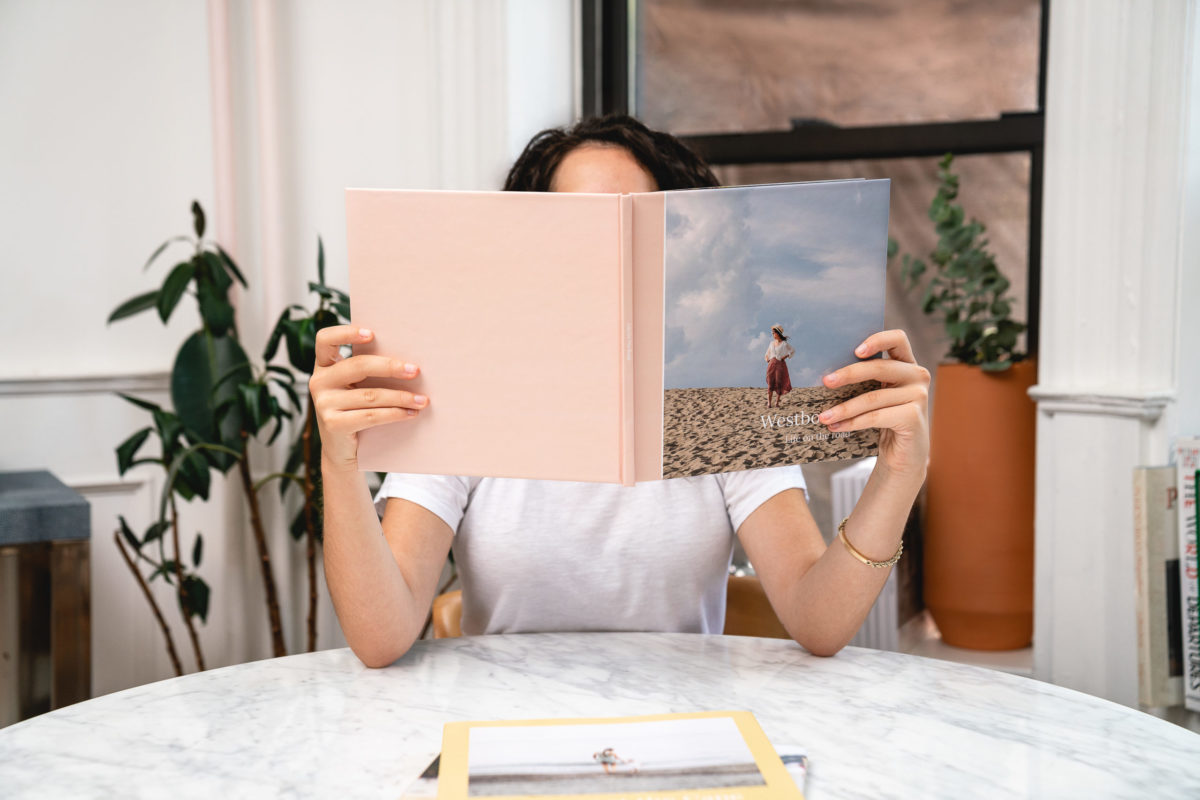 A woman holding a photo book up to her face