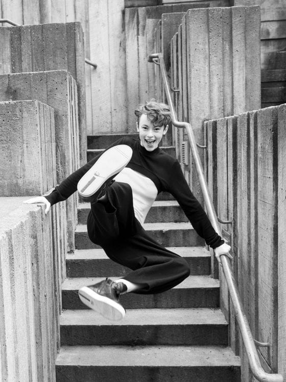 A woman high kicking off the ground as she jumps up the stairs
