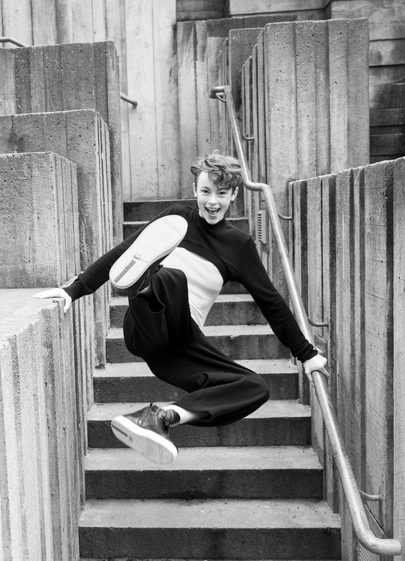 A woman high kicking off the ground as she jumps up the stairs