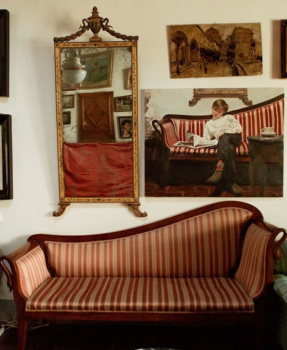 A picture of a living room with a few sofas and a wall covered with art