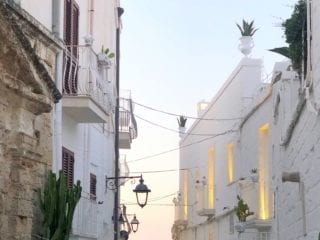 a view of a narrow alleyway between two white buildings that leads to the ocean